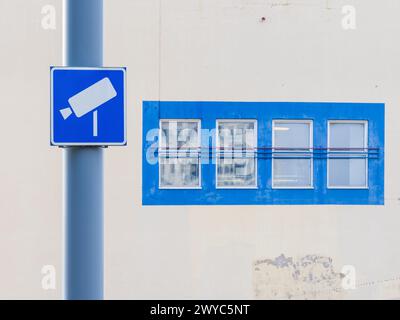 A Toll Road camera, indicated by a nearby sign, is mounted on a tall pole in front of a building with a row of windows. The backdrop suggests an urban Stock Photo