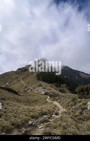 The peak of a mountain barely visible through dispersing clouds, creating an ethereal landscape of mystery Stock Photo