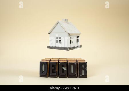 levitating house model miniature over Decor word written with stamp letters on beige Stock Photo