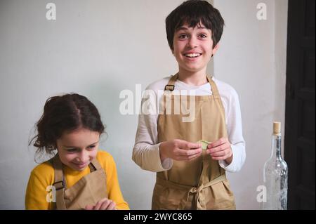 Authentic portrait of adorable children making dumplings at home kitchen Stock Photo