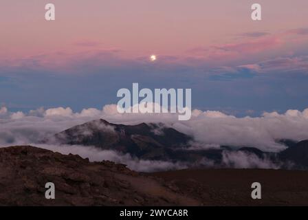 A moonrise after sunset with clouds rolling over the mountains Stock Photo