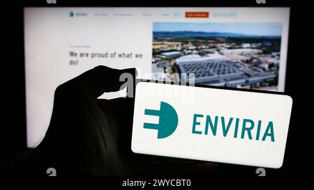 Person holding cellphone with logo of German solar company ENVIRIA Energy Holding GmbH in front of business webpage. Focus on phone display. Stock Photo