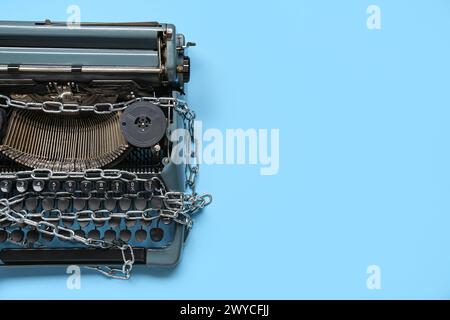 Vintage typewriter with chains on blue background. Printing ban concept Stock Photo