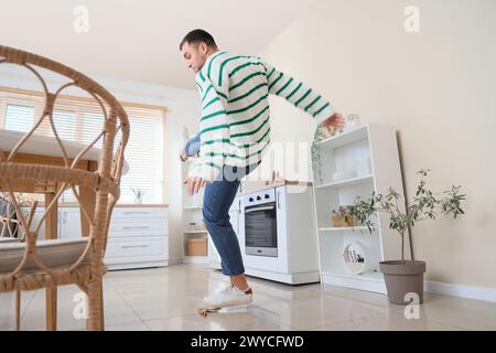 Young man falling after slipping on banana peel in kitchen Stock Photo