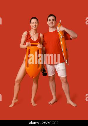 Lifeguards with ring buoy, rescue tube and binoculars on red background Stock Photo