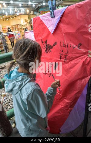 Girl carefully paints calligraphy on a large sky lantern to make a wish for the Chinese New Year Stock Photo