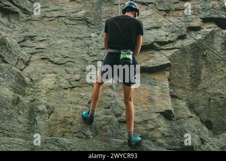 Young man in equipment doing rock climbing outdoors. Training area for outdoor activities. Extreme sport. Stock Photo