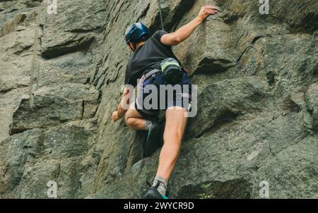 Young man in equipment doing rock climbing outdoors. Training area for outdoor activities. Extreme sport. Stock Photo