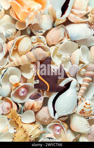 Homemade fish on a background of colored shells and  pearls. Natural shell background. Stock Photo