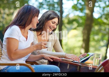 Looking a tablet. Women sisters 35 and 40 years taking coffee on a terrace. Donostia. San Sebastian. Gipuzkoa. Basque Country- Spain. Stock Photo