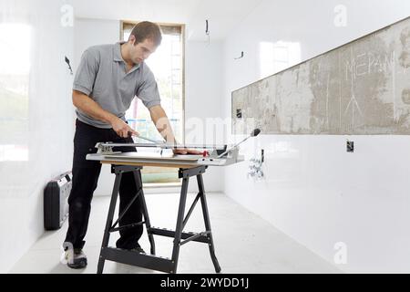 Bricklayer cutting tile. Manual tile cutter. Construction Industry. Stock Photo