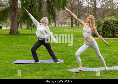 Two women of different ages practicing yoga in the park. Stock Photo