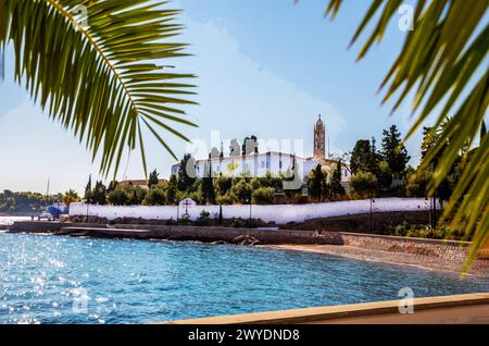 Small beach along coastline  Orthodox christian church  on  idyllic Greek islands (Spetsesor another Hydra. Crete, Mykonos, Phodes, Santorini)  Idylli Stock Photo