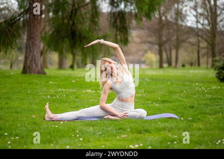 Woman doing side stretch in yoga pose outdoors. Stock Photo