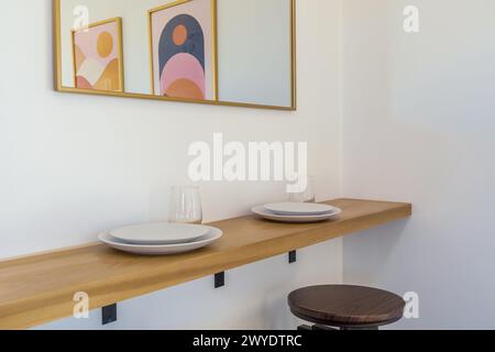 Breakfast bar floating shelf with white plates, glasses, stools in modern bohemian desert home Stock Photo