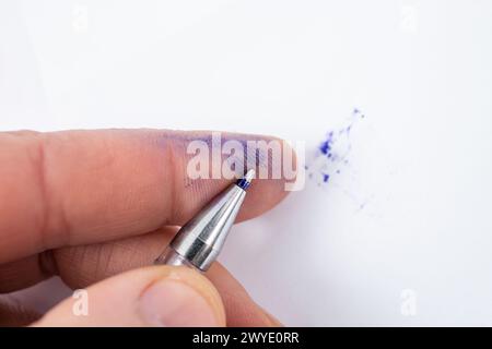 Ball point pen spilling blue ink on index finger print , soft focus  macro Stock Photo