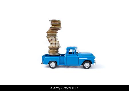 Die cast pickup toy carrying  a high stack of coins, isolated on white background, soft focus Stock Photo