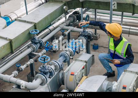 engineer male work checking water pipe inspecting valve testing water pump. Stock Photo