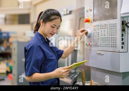 Engineer women control operate CNC industrial machine in metal production workshop. Asian young female industry worker. Stock Photo