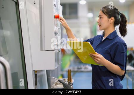 Engineer women control operate CNC industrial machine in metal production workshop. Asian young female industry worker. Stock Photo