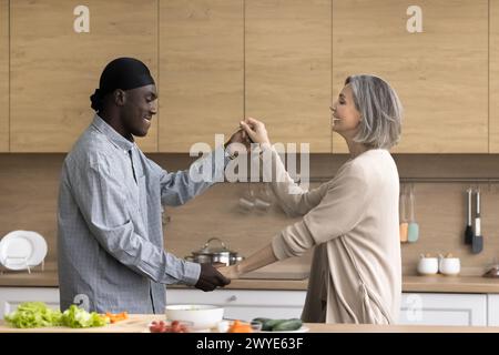 Happy multiethnic couple dancing in the kitchen Stock Photo