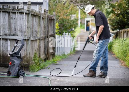 Man cleaning driveway using an electric water blaster. Stock Photo