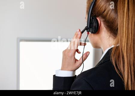 Helpdesk female employee in headset talks to a customer online. Stock Photo