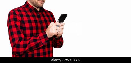 Man in red casual shirt messages online using his mobile phone on white background. Stock Photo
