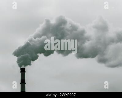Chimney white smoke on a gray sky. Smoking chimney. Clouds of thick smoke polluting the air against the sky. Stock Photo