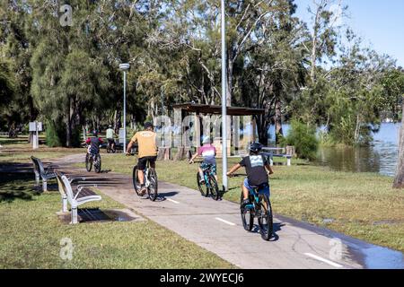 Sydney,Australia father and three sons ride their mountain bikes along a bike path beside Narrabeen lagoon lake, NSW,Australia Stock Photo