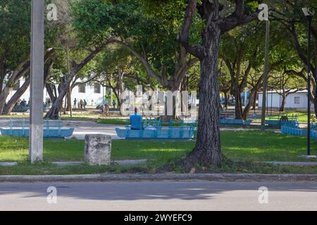 A lonely person sitting on a square bench in Havana, Cuba Stock Photo
