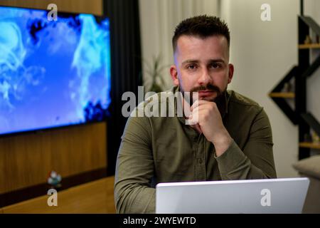 A young bearded Albanian  man working on his notebook from home. Stock Photo