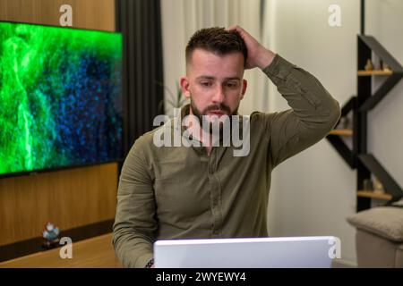 A young bearded Albanian  man working on his notebook from home. Stock Photo