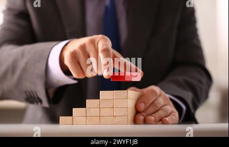 Male hand holds red wood block of stair Stock Photo