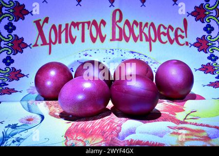 Painted red eggs lie on the fabric with the inscription Christ is Risen. Stock Photo