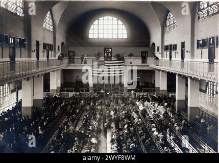 Immigrants seated on long benches, Main Hall, U.S. Immigration Station Stock Photo