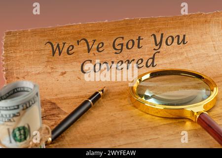 Text sign showing We Ve Got You Covered on papyrus next to a magnifying glass and money Stock Photo