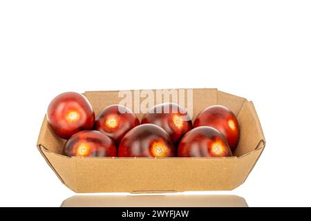 Several ripe black cherry tomatoes in a paper plate, macro, isolated on white background. Stock Photo