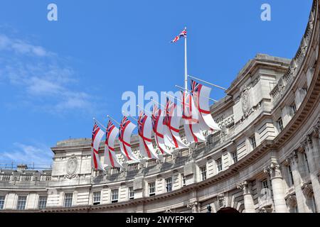 White Ensign flags flying on Admiralty Arch which connects The Mall and Trafalgar Square in London Stock Photo