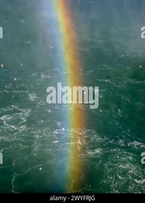 Rainbow in the mist of Niagara Falls over Niagara river Stock Photo