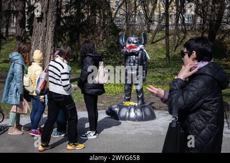 April 5, 2024, Kyiv, Ukraine: People spend time in the park next to the monument depicting the cartoon character Stitch from the cartoon 'Lilo and Stitch' in military uniform, erected in honor of the Ukrainian sniper Ihor Voevodin with nickname Stitch, who died in battles with the Russian army, in central Kyiv. Ukrainian student Ihor Voevodin volunteered for the front after the Russian invasion and served as a sniper in Azov regiment. Ihor Voevodin was killed in August 2023 on a combat mission in Luhansk region, Ukraine. (Credit Image: © Oleksii Chumachenko/SOPA Images via ZUMA Press Wire) EDI Stock Photo