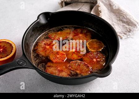 Traditional orange tasty sauce for French crepe Suzette in a cast iron pan on light table. Stock Photo