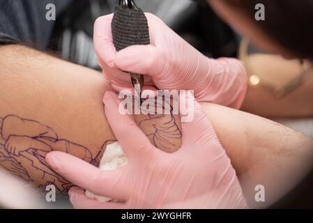 Hands with pink surgical gloves, performing a tattoo Stock Photo