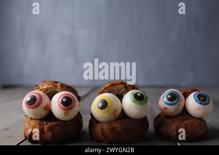 Cakes eclairs with eyes on a gray background with space for copyspace text. Cooking for Halloween. Funny Scary Food. Stock Photo