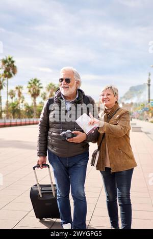 Older Caucasian tourist couple smiling looking and pointing interest places. Senior tourism people. Stock Photo