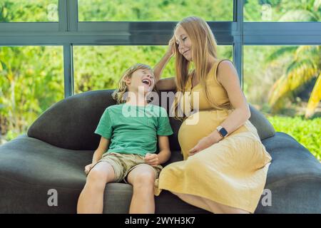 Pregnant mother and son are talking and spending time together at home. Little child boy looking at her mother pregnant tummy. Pregnancy, family Stock Photo