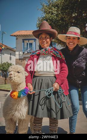 Cusco, Peru - March 2024. Ladies from Cusco pose with their llamas and alpacas and tourist for the photo, near the plaza. Cusco, Peru. Stock Photo