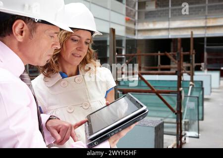 Architect and client with tablet PC in construction site. Stock Photo