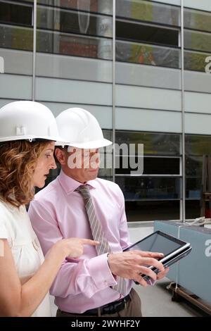 Architect and client with tablet PC in construction site. Stock Photo