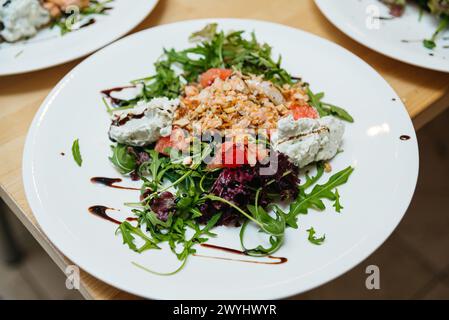 Fresh arugula and grapefruit salad topped with cream cheese, nuts, and shredded salmon fillet, finished with a balsamic drizzle. Stock Photo